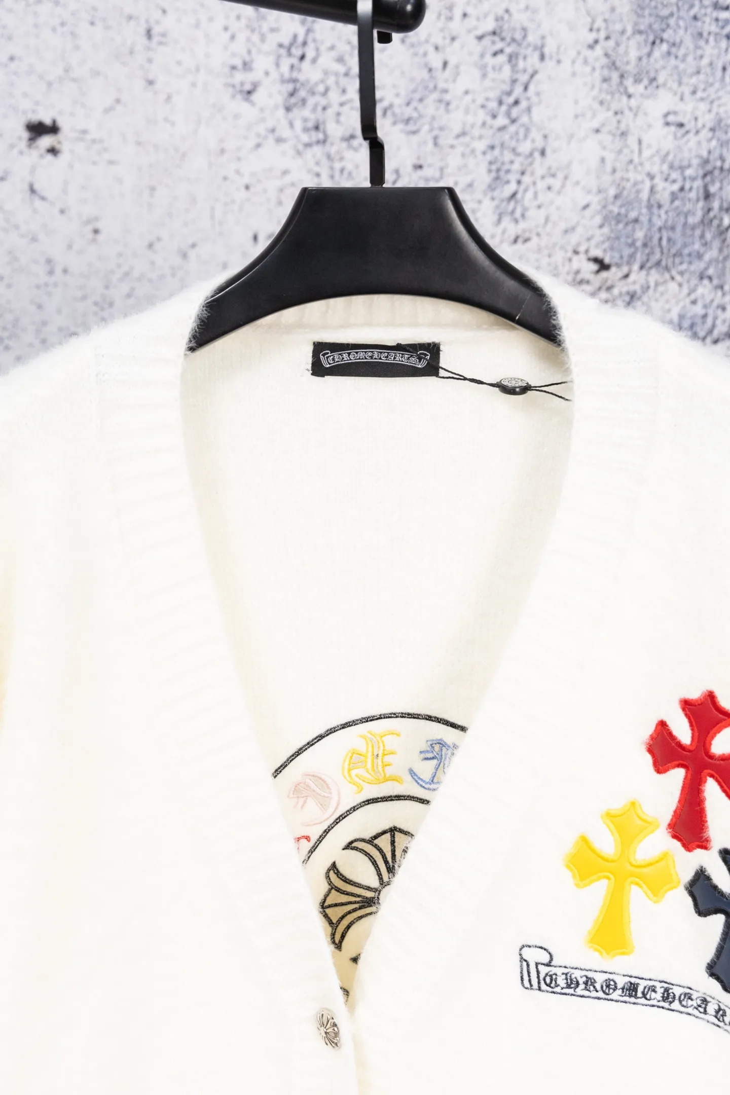 P300 Chrome Hearts CH Chrome Hearts 2026 new cross loose knitted V-neck cardigan Fabric: Made of plush textured knitted material, soft to the touch and with a lazy atmosphere; Decoration: Red, yellow, and black cross ornaments on the chest, paired with brand logo patches, which are iconic elements of street fashion brands (such as Chrome Hearts style), enhancing visual recognition; Version: Loose version + single-row metal button design, combining casual feeling and practicality. 2. Style and Adaptation Style: It combines dark street style and gentle knitted texture, which belongs to the tone of "sweet and cool mix"; Scenario: Can be worn with a T-shirt/suspender to create a daily street look, or can be layered with a shirt for light casual wear. Color: Black White Size: M L XL